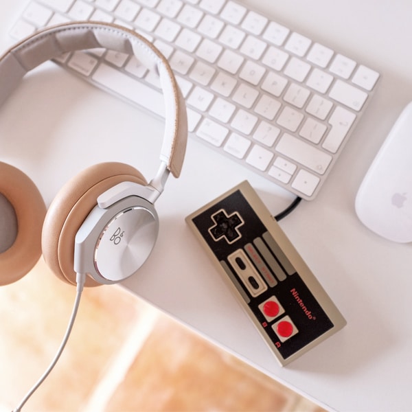 a desk with a computer keyboard, a mouse, some headphones and a retro Nintendo videogame controller. Getting ready to translate at Aguilar and Mahon translation services.